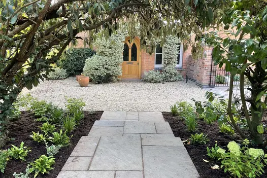 3 wide steps of Raj Green Indian sandstone paving descend to gravel drive crossing house front. Design by Wilson Associates.