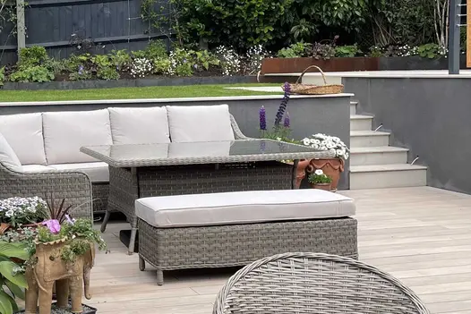 Steps leading away from decking area made from Faro Porcelain, have 20mm Bullnose edge and go up to lawn with bordering plants.