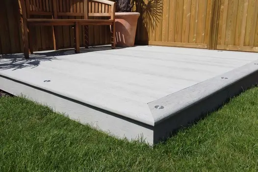 Curve-backed bench on Smoked Oak Millboard composite decking with lights set into edge boards. Built by Monarch Lawn and Landscape.