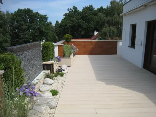 Large decking area using limed oak millboard on balcony terrace sees large trees in the background.