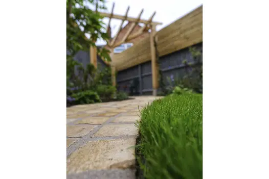 Focused, close-up shot of Mint Sandstone Setts used on curved cobble path with freshly trimmed grass running alongside.