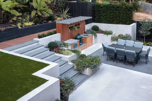 2-level garden with retaining walls of upper level faced in Off White exterior cladding. 10 dark grey steps descend to lower level.