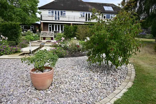 Mint Sandstone setts line a circle of grey pebbles with terracota plant pot surrounding the cobbles.