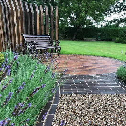Circle of Lugano brick paving, set between lawn and bed, encloses Bromley clay pavers uk laid within. Built by Outsiders Landscaping.