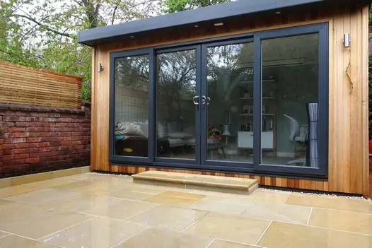 Garden showcases Harvest Edging Stones with matching sandstone paving and bullnose steps, leading from a patio to an outhouse.