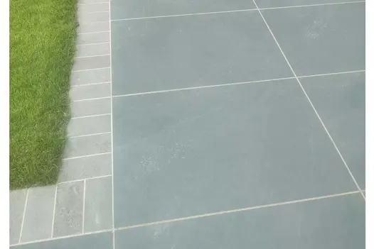 Corner of lawn edged with Platinum Grey Porcelain Setts laid perpendicular and jointed with pale mortar by Healey Paving Services.