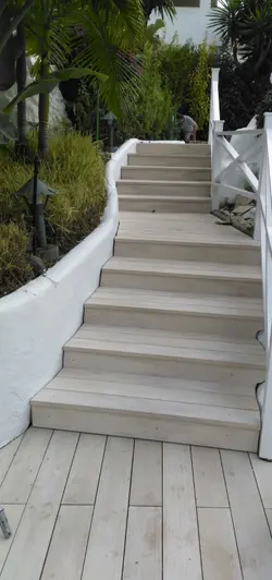 Steps running up white rendered wall are clad with polar designboard composite decking with white hand rail.