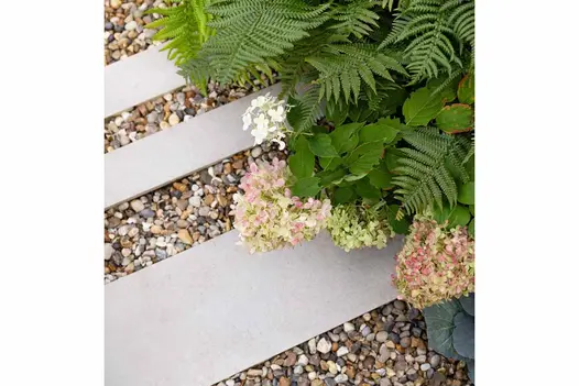 3 strips of florence grey porcelain have pebbles laid in between, with green and pink plants spilling out from the flowerbeds.