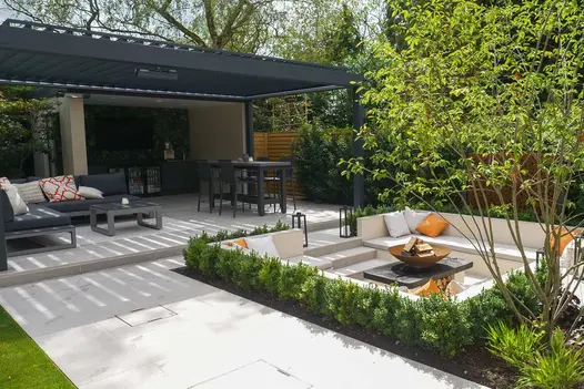 Sunken seating area around patio, all using Florence Grey Porcelain Paving, pergola in the background creates shadows.