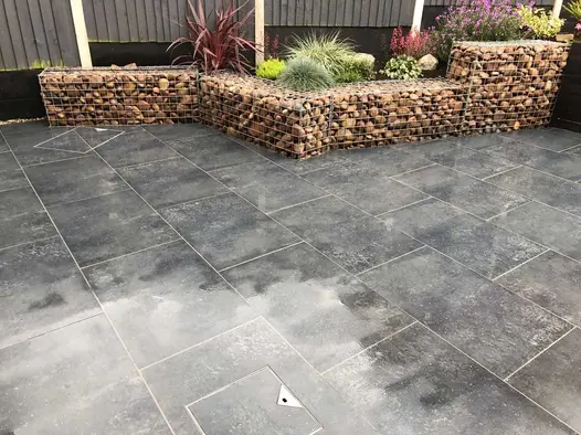 Charcoal porcelain patio with raised planters constructed from gabion cages filled with large river washed pebbles.