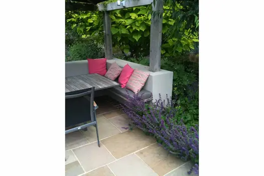Lavender planted next to outdoor furniture, with neat Raj Green Indian Sandstone Paving laid underneath.