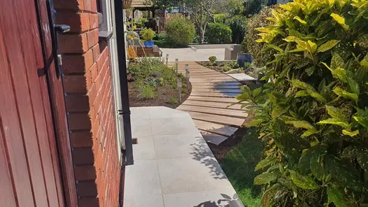 Curved rovere porcelain path set amongst planting and snaking its way towards a patio area.