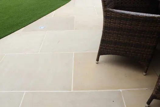 Chair sits on Harvest sawn sandstone 900x600 paving slabs with white joints. Creates curved edge to lawn.