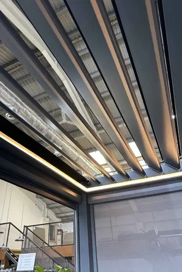 Side view of the Deluxe Anthracite Grey Metal Pergola with one side blind down and the LED lights on display, available in 4x4.