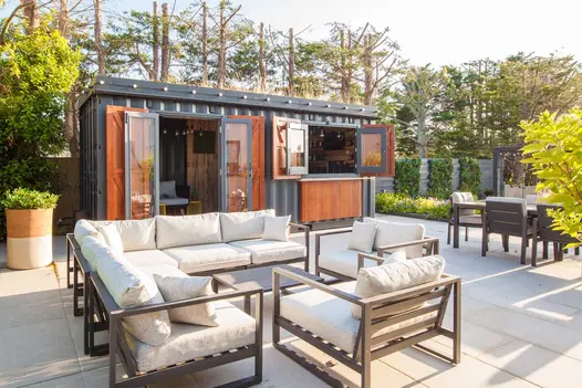 Lounge set sits Florence Grey porcelain slabs outside bar and garden room in converted shipping container. Design by Simon Orchard.