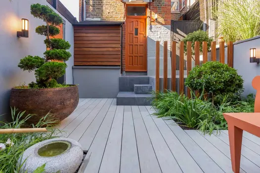 Decked courtyard by Epoch Garden Design, with planters and water outside front door with 3 steps in Slab Coke Porcelain slabs.