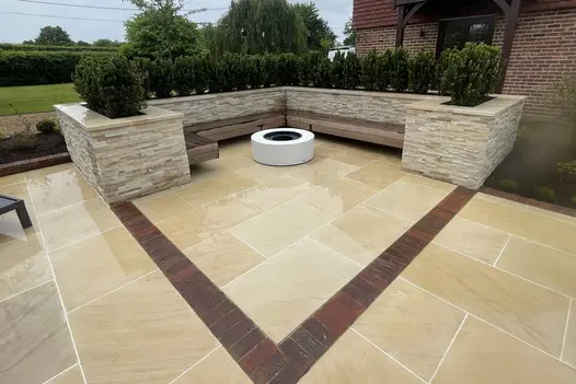 Outdoor seating area with built-in benches, surrounded by cladded planters, paved with Harvest Sawn Sandstone.