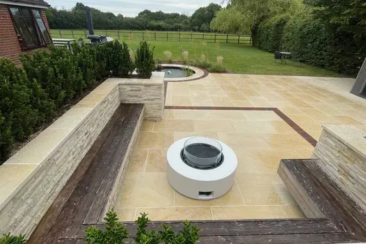 Fire pit seating area with integrated benches against stone-clad planters. Harvest Sawn Sandstone enhances the warm and inviting atmosphere.