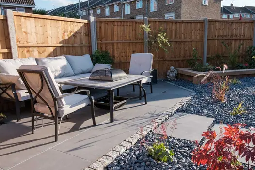 Steel Grey porcelain patio edged in Silver Grey granite setts and surrounded by a planted decorative gravel feature.