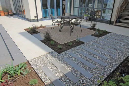 Steel Grey Porcelain Planks as stepping stones, guides the way across garden. Clay-paved area provides a space for a garden dining set.