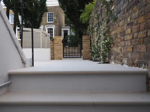 Faro Porcelain 36mm Bullnose steps on white concrete stairway ascending towards brick wall and front gate.