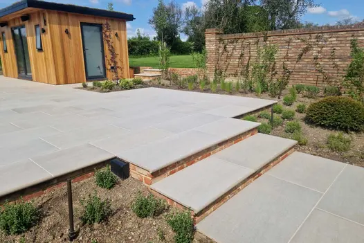 Porcelain patio with steps leading up to a wooden shed, featuring Urban Grey Porcelain 36mm Bullnose Steps.