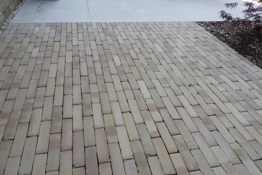 Westminster clay pavers laid running bond edged on 2 sides by planted bed and paving slabs. Laid by Montrose Landscape Gardening.