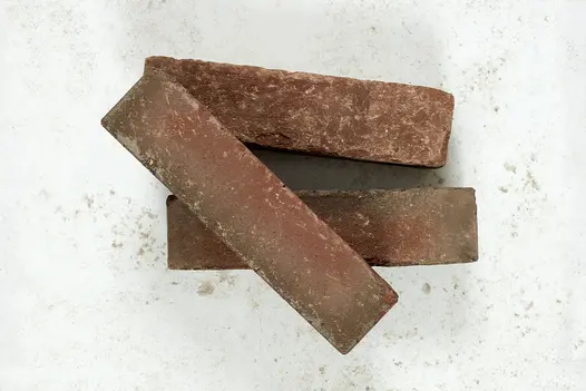 2 Winton clay pavers showing smooth and sanded sides sit on pale background, with 3rd brick at an angle on top.